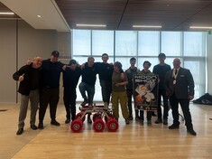 Mr. Dubeau and students standing side by side with a miniature rover vehicle infront of them